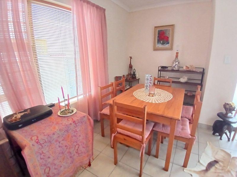 A functional dining area featuring tiled flooring and natural light through venetian blinds, offering a neutral space ready for modern updates.