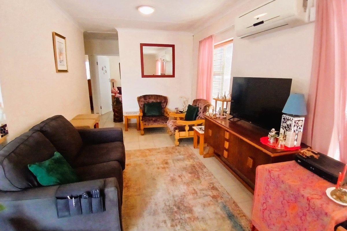 A functional living room featuring tiled flooring, a wall-mounted split-system air conditioner, and neutral wall finishes.