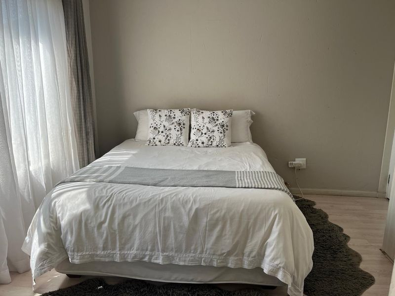 A well-lit bedroom featuring light-toned laminate flooring and neutral wall finishes, providing a clean and comfortable sleeping space.