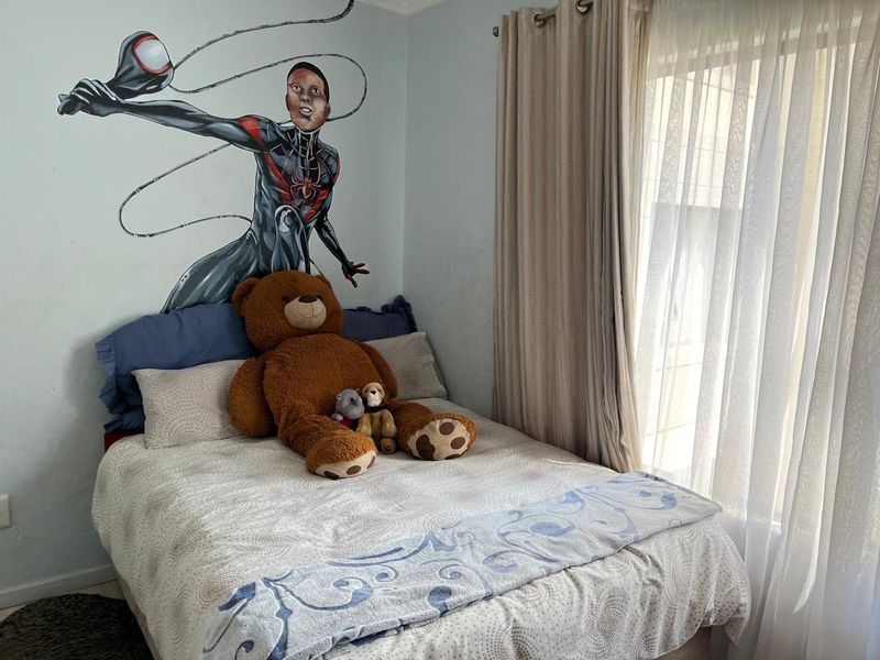 A bedroom featuring a wall mural and natural light provided by a window with installed curtain tracks.