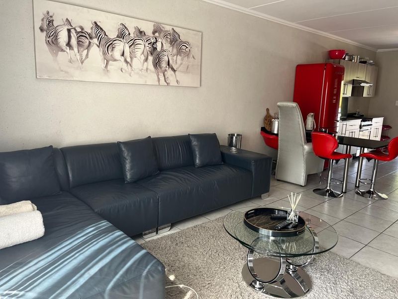 An open-plan living and kitchen area featuring tiled flooring and a functional kitchen layout with built-in appliances.