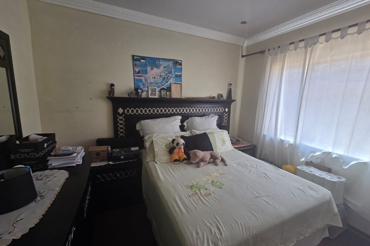 A bedroom featuring crown molding and recessed lighting, with a window dressed in sheer curtains.