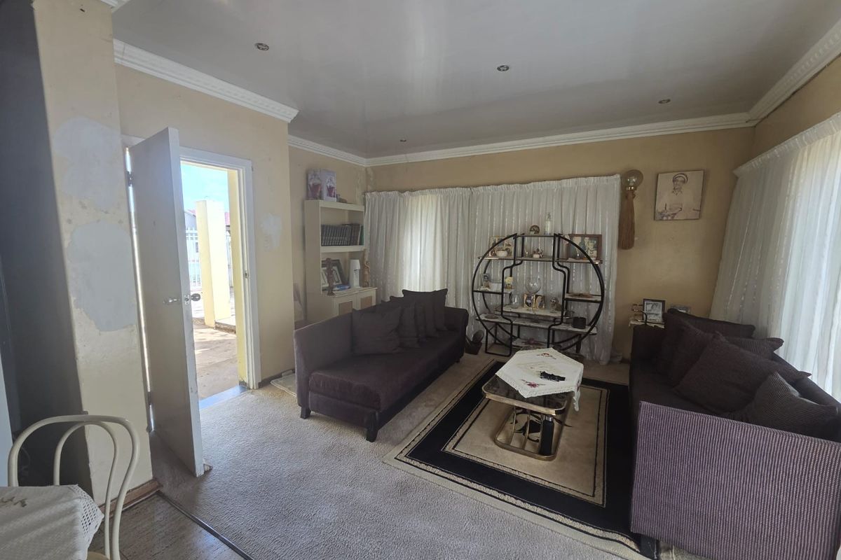 A living room featuring crown molding, recessed lighting, and built-in shelving, currently showing signs of wear on the wall finishes.