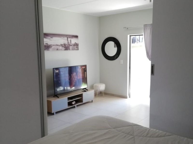 A bedroom featuring tiled flooring, a recessed ceiling detail, and a sliding door providing access to an outdoor area.