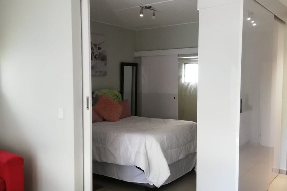 A bedroom featuring modern tiled flooring and a functional sliding door partition, providing a flexible layout within the apartment space.