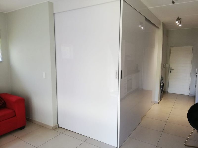 Open plan living area featuring modern tiled flooring, recessed lighting, and a large white sliding partition wall for flexible space management.