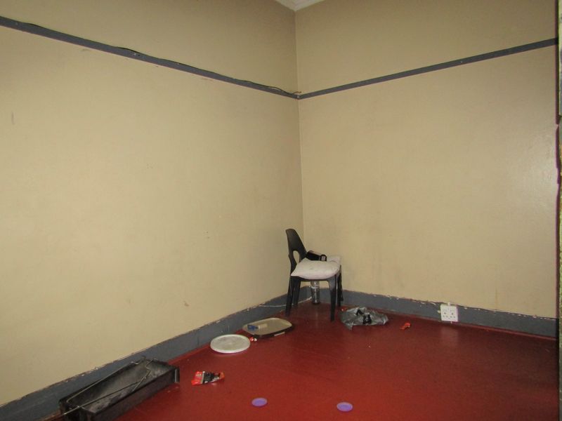 A vacant bedroom featuring painted walls with a dado rail and a painted floor finish, suitable for renovation or restyling.