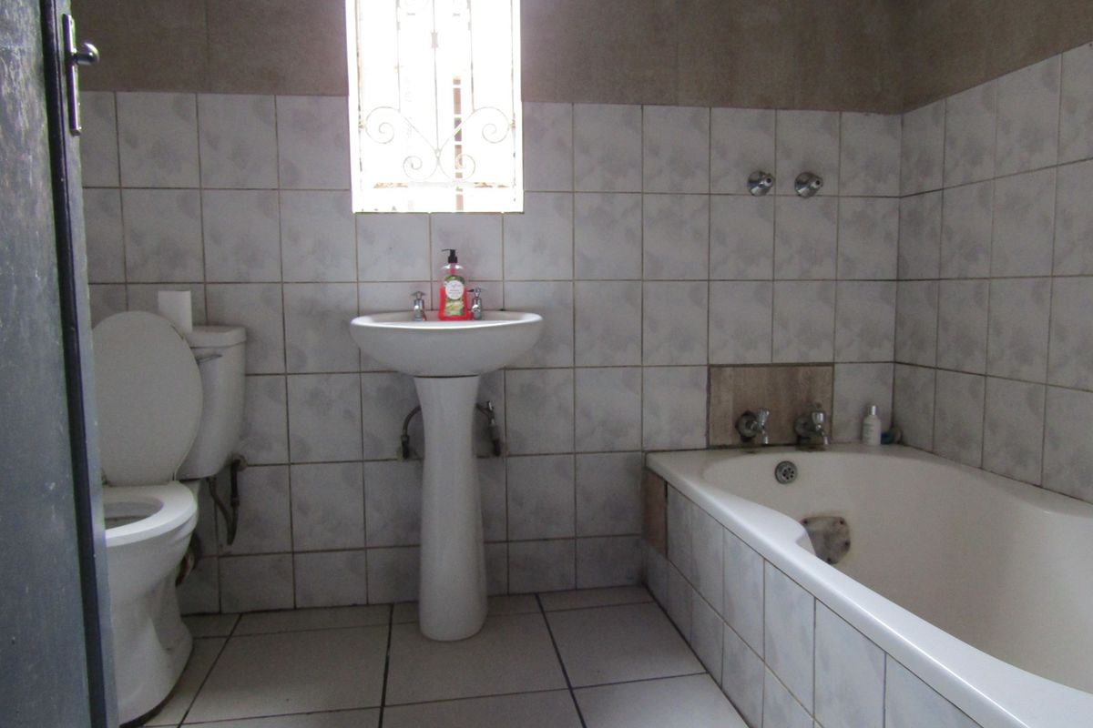 A functional bathroom featuring a pedestal basin, toilet, and built-in bathtub with tiled finishes throughout.