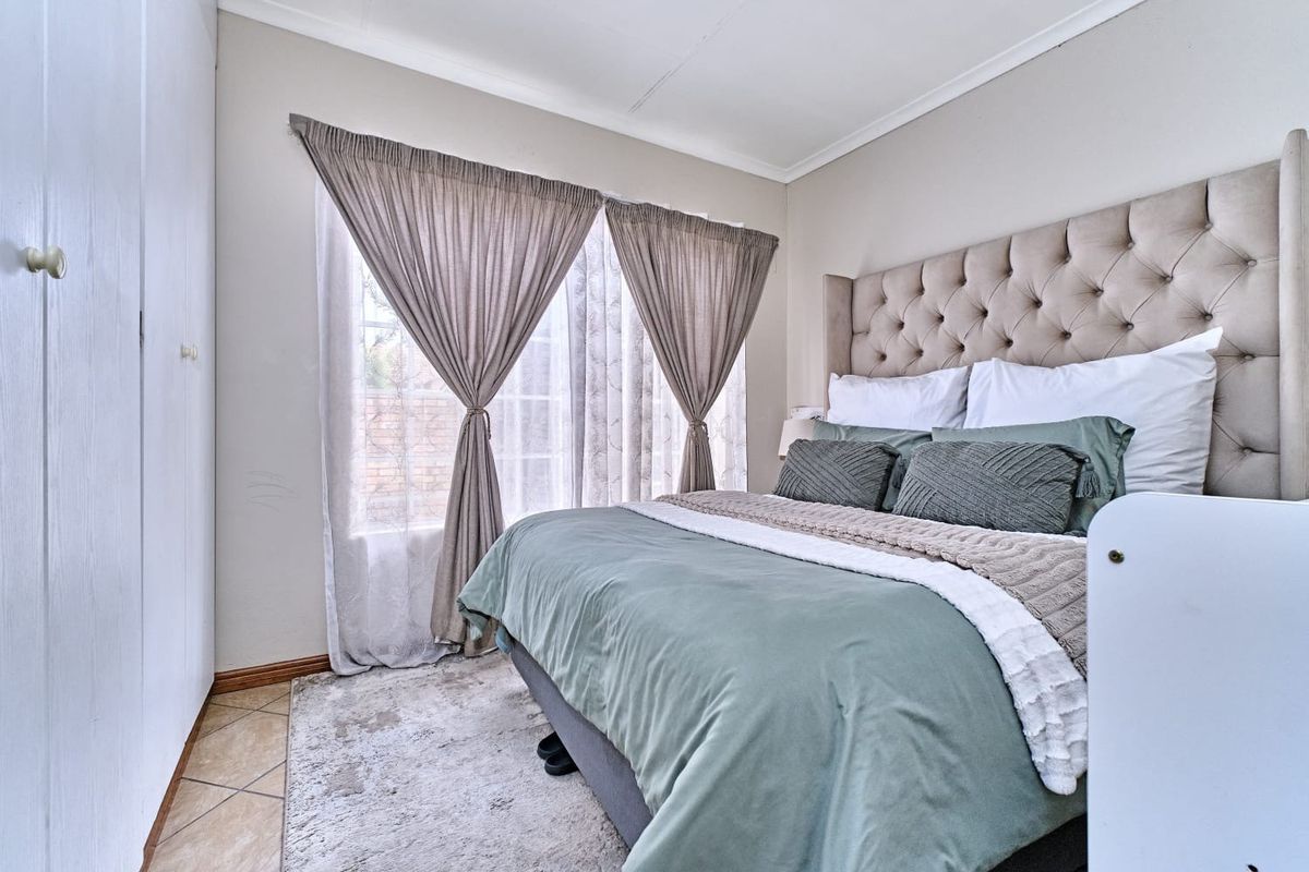 A well-lit bedroom featuring built-in cupboards, tiled flooring, and a coved ceiling, providing a comfortable and functional living space.