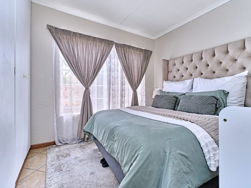 A well-lit bedroom featuring built-in cupboards, tiled flooring, and a coved ceiling, providing a comfortable and functional living space.