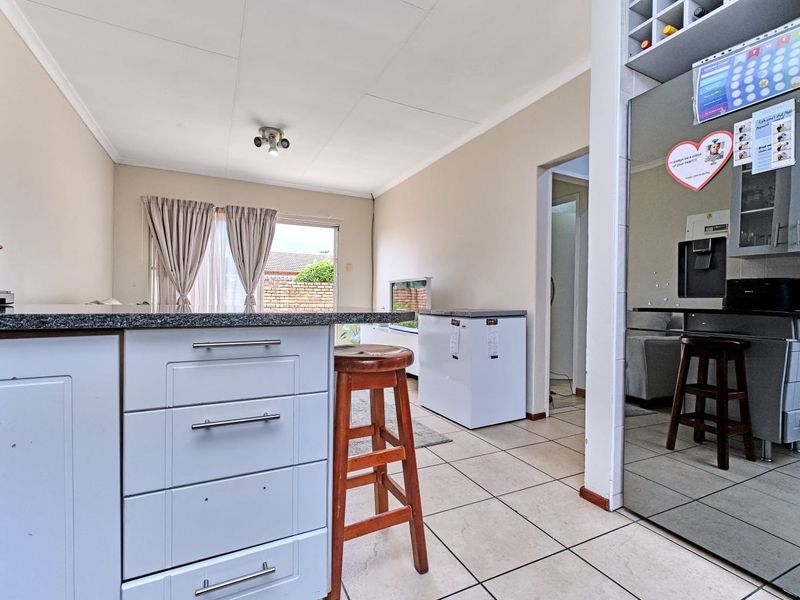 Open plan kitchen and living area featuring tiled flooring, granite countertops, and built-in cabinetry with direct access to the outdoor patio area.