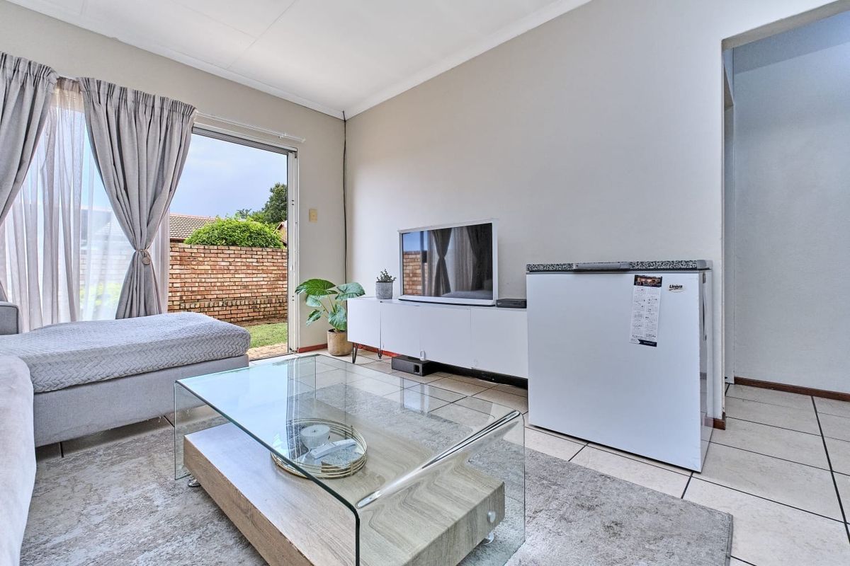 A bright living room featuring tiled flooring and a sliding glass door providing direct access to the outdoor area.