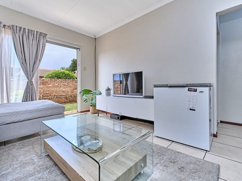 A bright living room featuring tiled flooring and a sliding glass door providing direct access to the outdoor area.