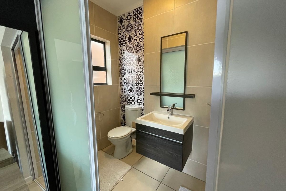 Modern bathroom featuring a wall-mounted vanity, tiled feature wall, and a sleek glass shower enclosure.