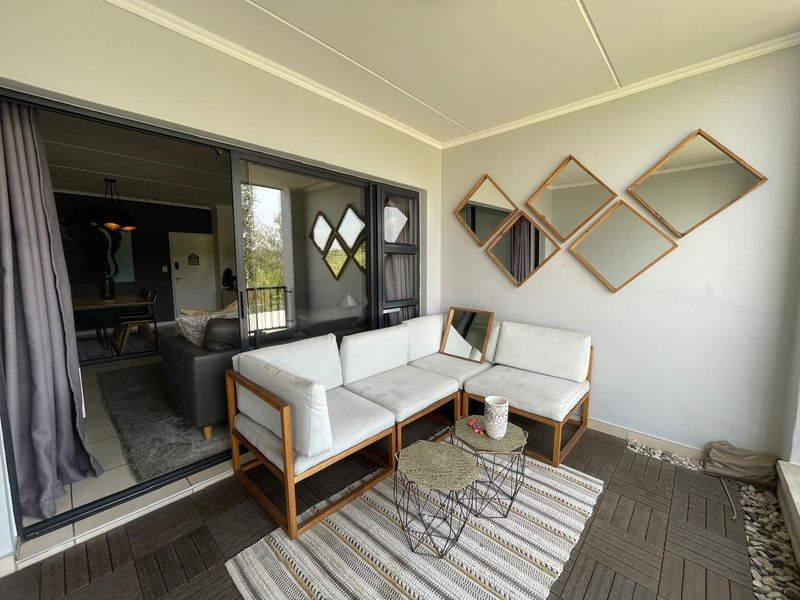 A covered balcony featuring dark decking tiles and a large sliding glass door providing seamless access to the interior living space.