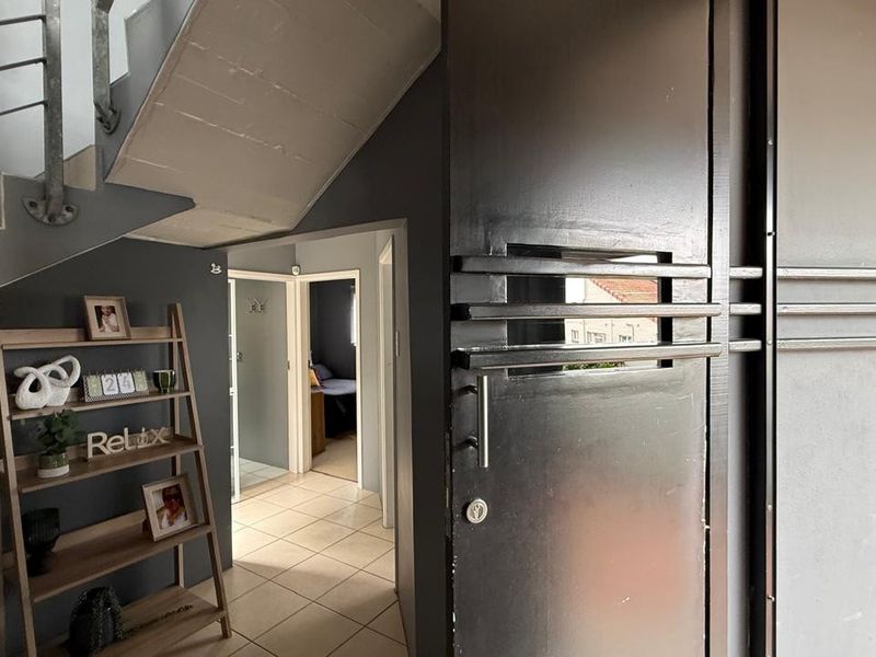 Entrance area featuring a modern security door, tiled flooring, and an internal staircase leading to the upper level.