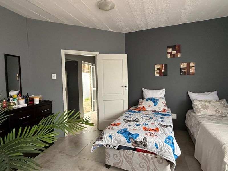 A bedroom featuring tiled flooring, dark grey painted walls, and a textured ceiling, with an internal door leading to an adjacent space.