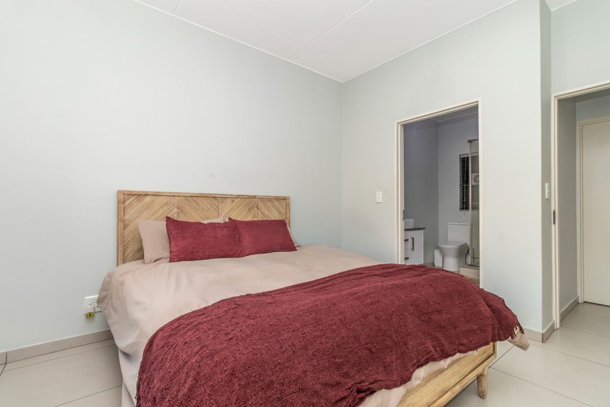 A well-maintained bedroom featuring neutral tiled flooring and direct access to an en-suite bathroom.