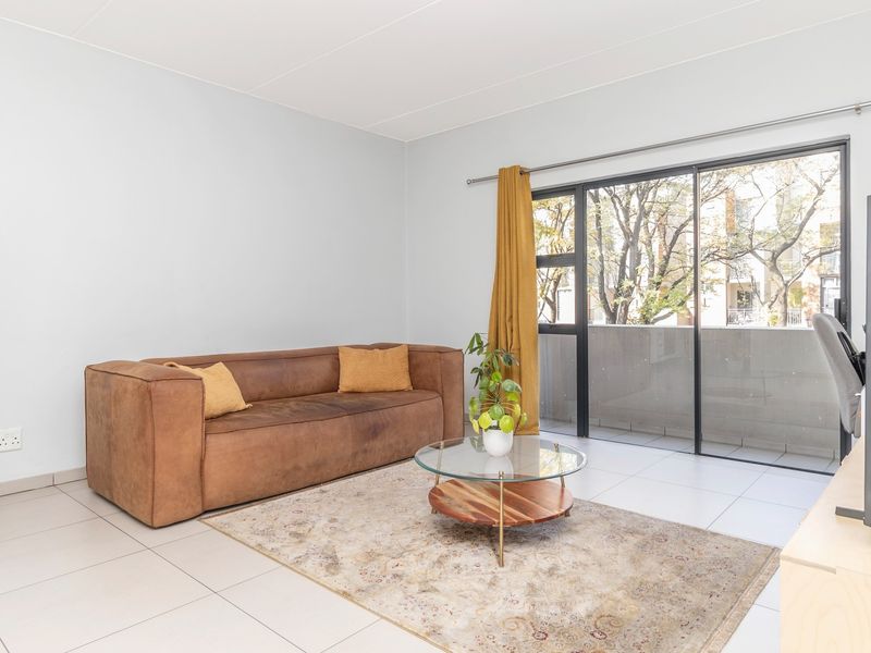 A bright living room featuring large sliding glass doors that provide access to a balcony and allow for ample natural light.