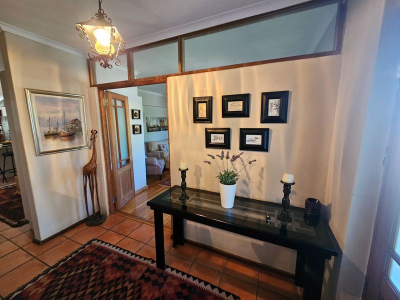 Welcoming entrance hall featuring terracotta floor tiles, a timber door frame, and a glass transom window, leading into the main living area.