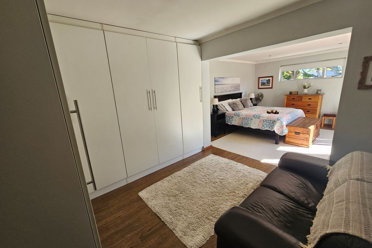 Spacious bedroom featuring extensive built-in wardrobes, laminate flooring, and a comfortable layout with integrated storage solutions.