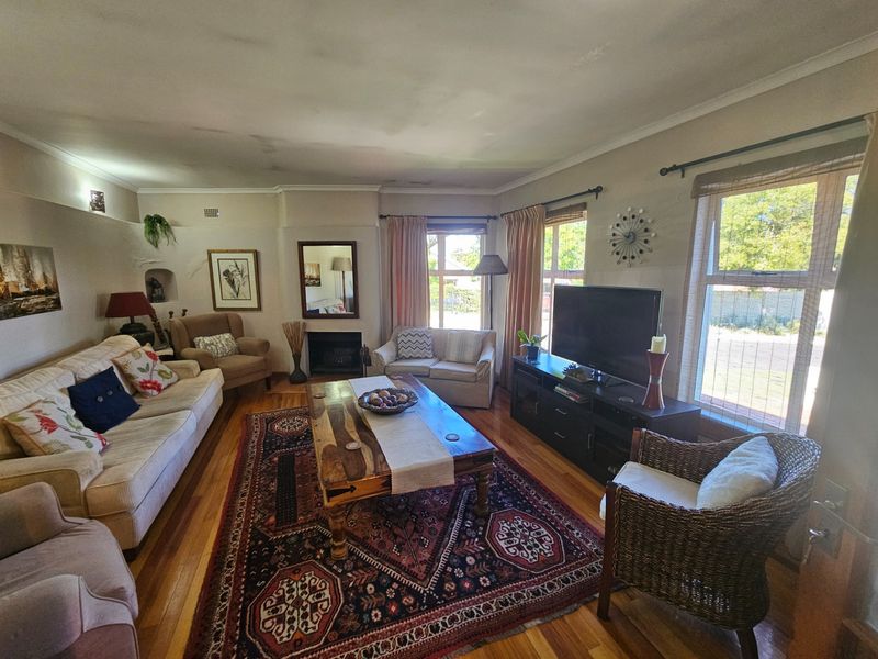 A spacious living room featuring hardwood flooring, a built-in fireplace, and large windows that provide ample natural light.