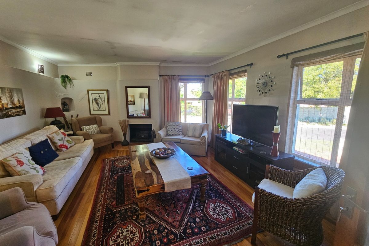 A spacious living room featuring hardwood flooring, a built-in fireplace, and large windows that provide ample natural light.