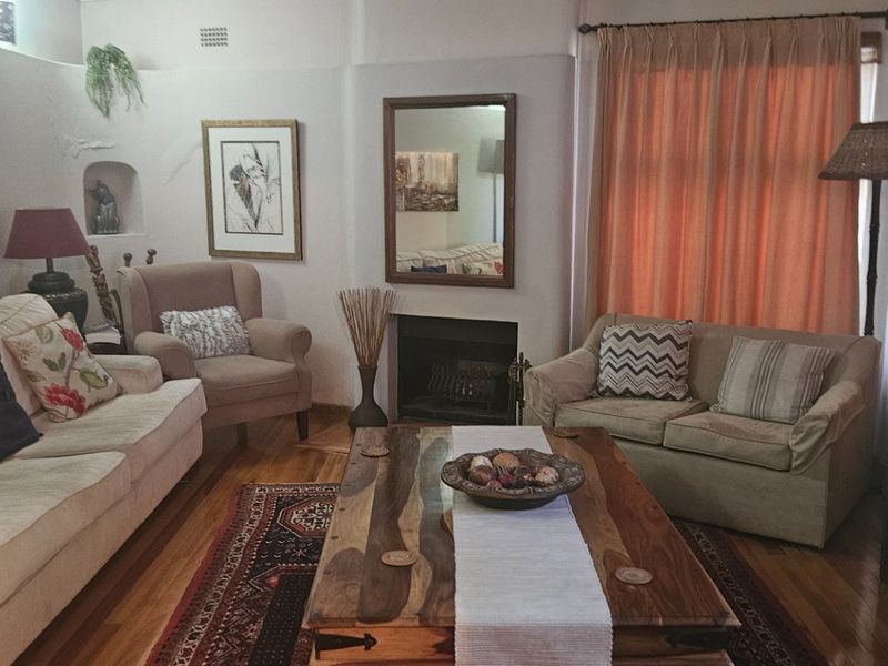 A cozy living room featuring hardwood flooring, a central fireplace, and a recessed wall niche, offering a warm and traditional atmosphere.