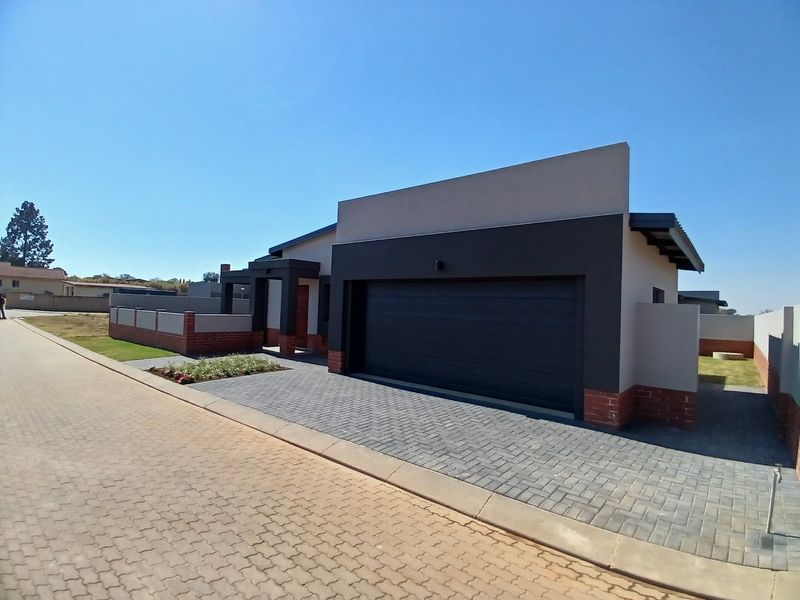 Modern front elevation of a house featuring a double garage, paved driveway, and contemporary brick and plaster exterior finishes.