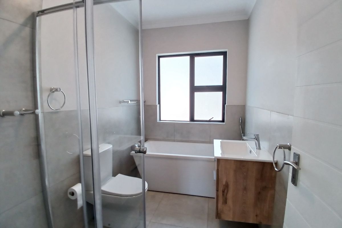 Modern bathroom featuring a glass-enclosed shower, a built-in bathtub, and a contemporary wall-mounted vanity with a ceramic basin.