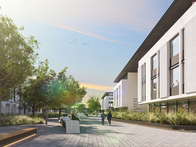 A modern office complex exterior featuring a landscaped pedestrian walkway, contemporary building facade, and integrated outdoor seating areas.