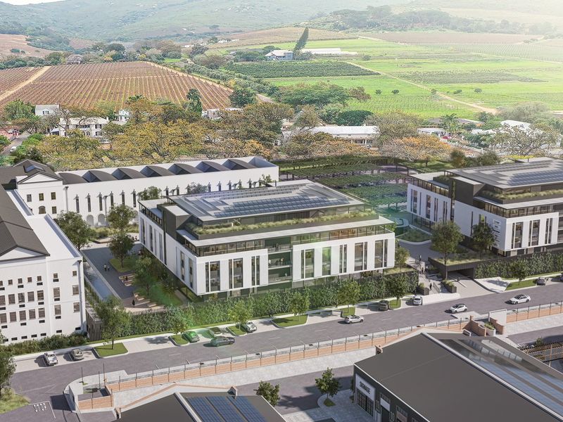 Aerial view of a modern office park complex featuring contemporary architecture, solar panels, green roofs, and landscaped outdoor spaces in a scenic setting.