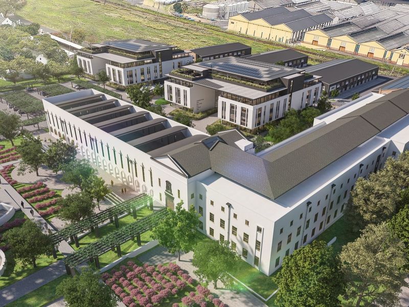 Aerial view of a modern office complex featuring multiple buildings, landscaped gardens, paved walkways, and dedicated parking areas.
