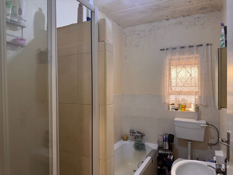 A dated bathroom featuring a shower, bathtub, and toilet, currently showing significant signs of wall and ceiling deterioration requiring maintenance or renovation.