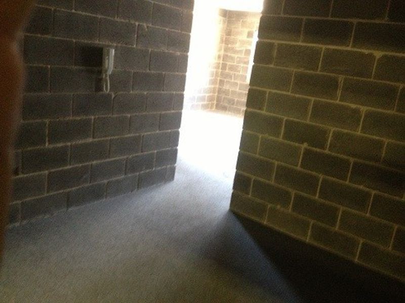 An industrial utility space featuring exposed brick walls and an integrated intercom system, offering a functional area with potential for various uses.