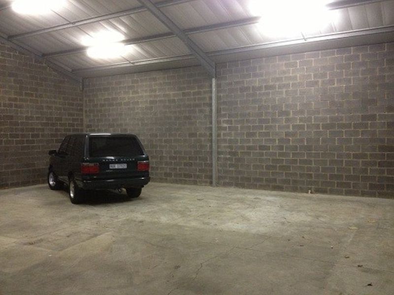 Spacious industrial garage featuring exposed concrete block walls, durable concrete flooring, and high-clearance metal roofing with overhead lighting.