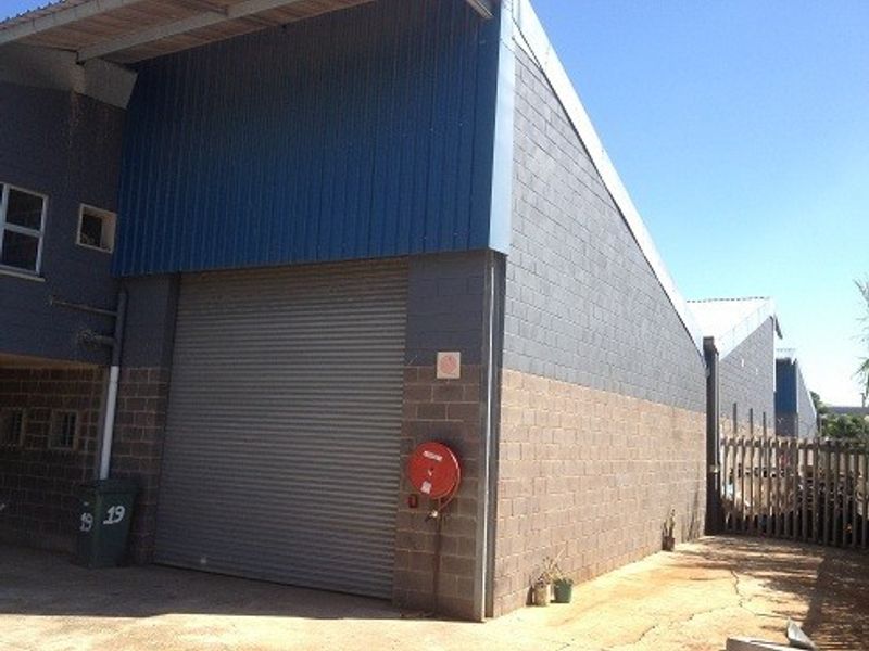 Industrial warehouse unit featuring a large roller shutter door, durable concrete block construction, and metal cladding exterior.