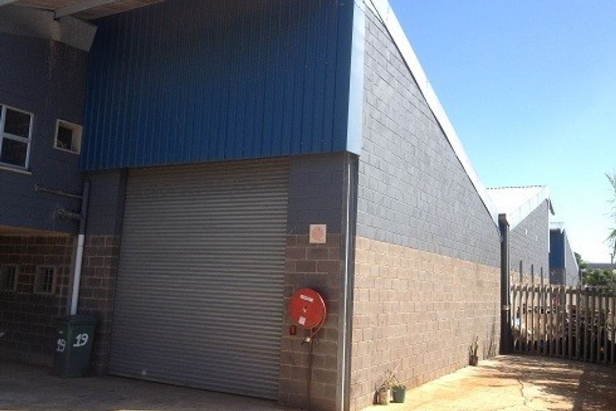 Industrial warehouse unit featuring a large roller shutter door, durable concrete block construction, and metal cladding exterior.