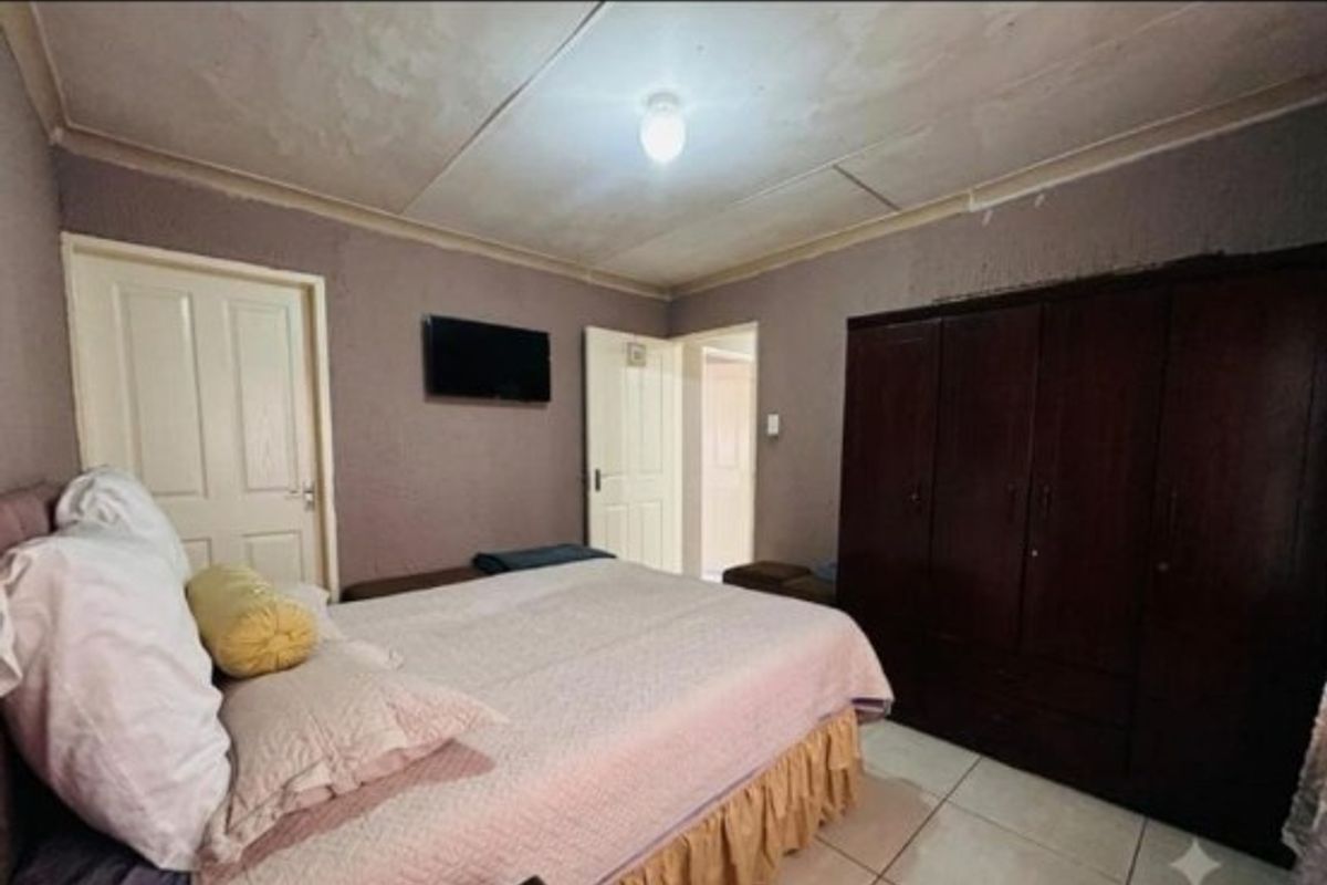 Bedroom featuring tiled flooring, built-in wardrobe, and ceiling coving. The ceiling shows visible signs of wear and requires maintenance.
