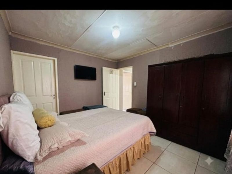 Bedroom featuring tiled flooring, built-in wardrobe, and ceiling coving. The ceiling shows visible signs of wear and requires maintenance.