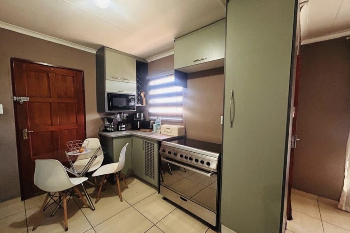 Compact kitchen featuring sage green cabinetry, tiled flooring, and a freestanding stove, providing a functional and efficient cooking space.