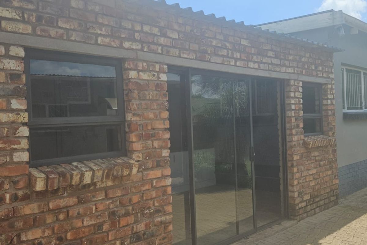 Rear exterior view of the property featuring face brick walls, sliding glass doors, and a paved patio area.