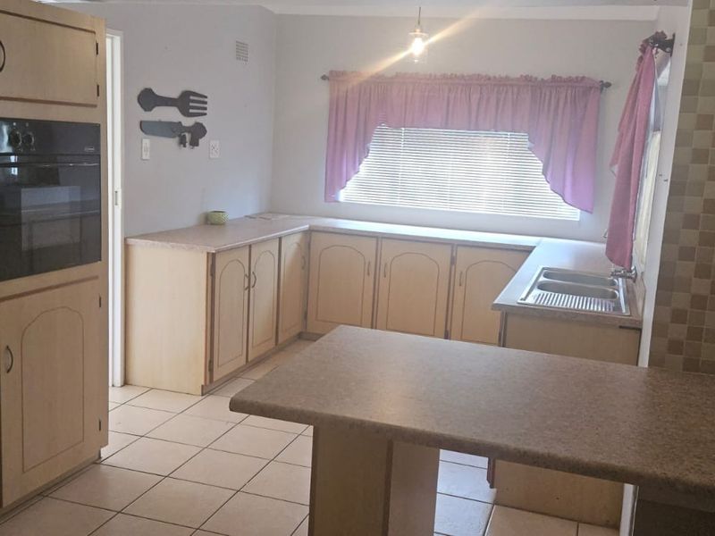 A functional kitchen featuring built-in cabinetry, a gas hob, integrated oven, double sink, and tiled flooring with a neutral backsplash.