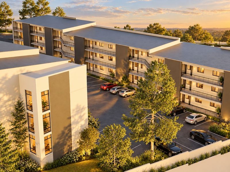 Aerial view of a modern multi-story apartment complex featuring dedicated parking, landscaped grounds, and private balconies at sunset.