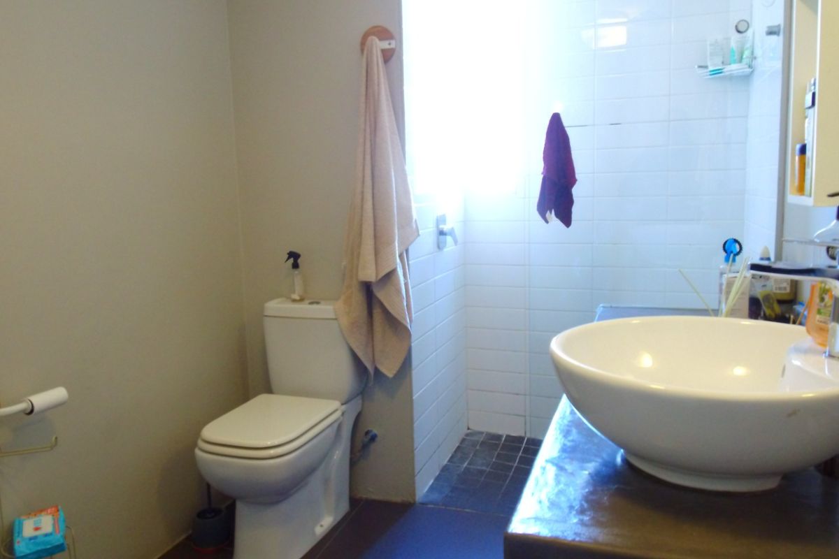 A functional bathroom featuring a modern vessel sink, a toilet, and a tiled shower area with neutral wall finishes.