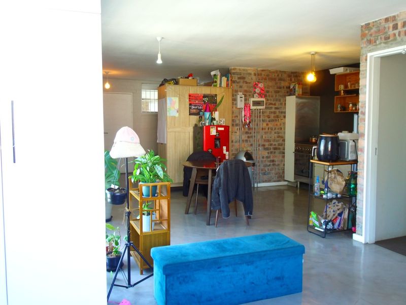 Open-plan living area featuring polished concrete floors and an exposed brick feature wall, creating an industrial-style aesthetic.