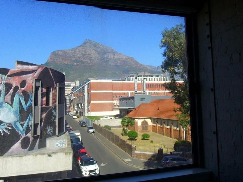 A framed view from an interior window looking out over a city street towards a prominent mountain.