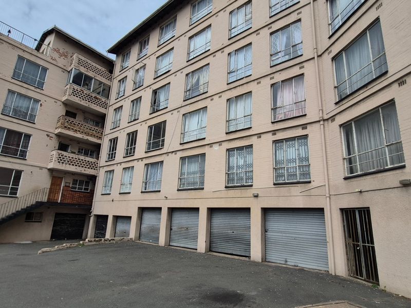Exterior view of the Blue Horizons apartment building featuring a multi-story facade, ground-level roller shutter garages, and an external staircase.