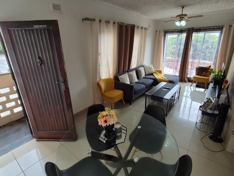 Open plan living and dining area featuring tiled flooring, a ceiling fan, and sliding glass doors leading to an outdoor balcony.
