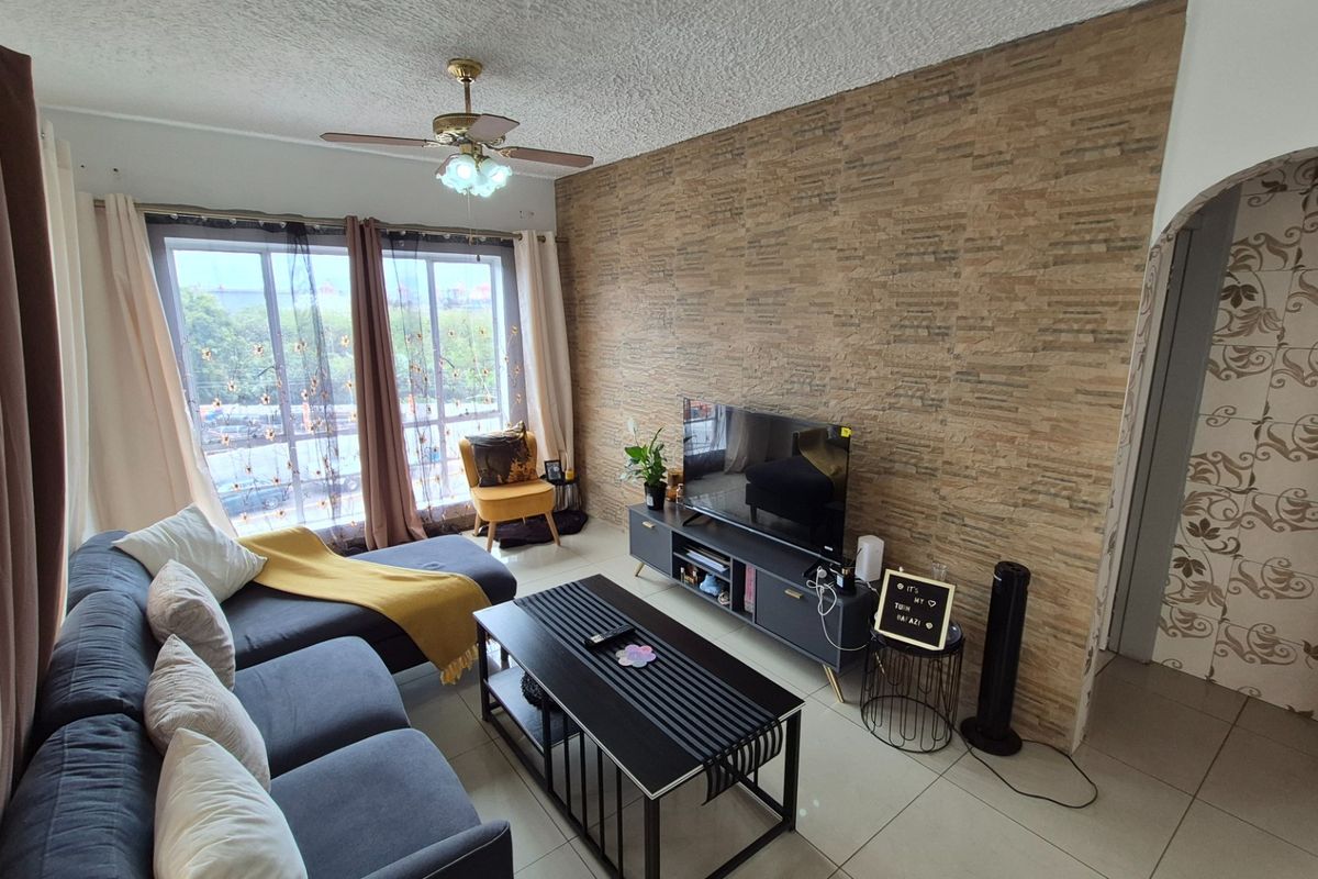 A comfortable living room featuring a textured stone veneer accent wall, tiled flooring, and a ceiling fan, with access to a balcony through sliding doors.